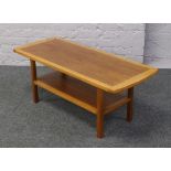 A teak two tier coffee table raised on square cut legs.