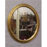 A gilt framed oval wall mirror.