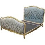 A painted French bed frame upholstered in teal silk with brass studwork.