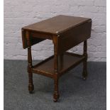 An oak two tier drop leaf tea trolley raised on circular and square supports.