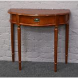 A hardwood demi lune side table with single drawer raised on reeded supports.