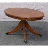 A mahogany oval top coffee table with strung inlay, raised over reeded supports and lion paw feet.