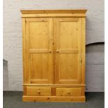 A carved pine double wardrobe over two drawer base.