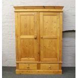 A carved pine double wardrobe over two drawer base.