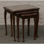 A nest of three mahogany occasional tables with glass inset tops.