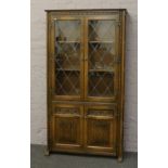 An Old Charm carved oak lead glaze bookcase over cupboard base with linen fold decoration.