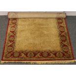 A large red and gold ground wool rug with floral decoration, 243cm x 161cm.