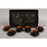 An oriental lacquered six place coffee set on tray with gilt decoration and painted landscapes.