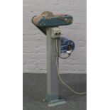 A 10cm belt sander mounted on a steel floor stand with 220 volt motor.