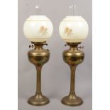 A pair Victorian brass oil lamps one raised on a column and later converted to electric.