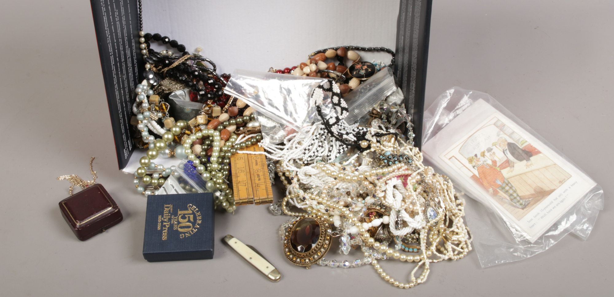 A box of costume jewellery to include glass beads, simulated pearls, brooches etc.