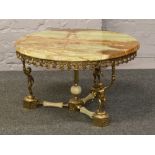 A circular onyx coffee table with gilt cherub supports.