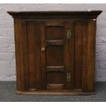 A panelled oak wall hanging corner cupboard.