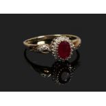 A 9ct gold halo cluster ring set with a ruby under a border of diamonds, size T.