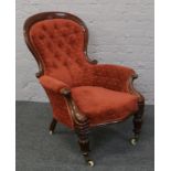 A spoon back arm chair with deep button upholstery, raised on carved supports.