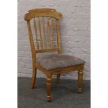 A light oak spindle back chair with upholstered seat.