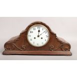 An 8 day oak cased dome top mantle clock decorated with scrolls.