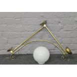 A brass effect wall mounting light with opaque spherical shade.