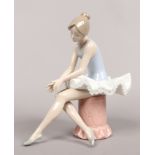A glazed Nao seated ballerina by Lladro manufactured in Spain.