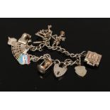 A silver charm bracelet to include key charms, bible charm, love heart lock charm etc.