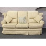 A cream upholstered three seat sofa with fire certificate.