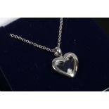 A 9ct white gold heart shaped pendant with floating diamond on chain.