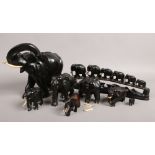 A group of carved hardwood elephants with ivory tusks.