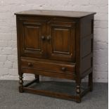 An Ercol carved and panelled side cabinet with single drawer.