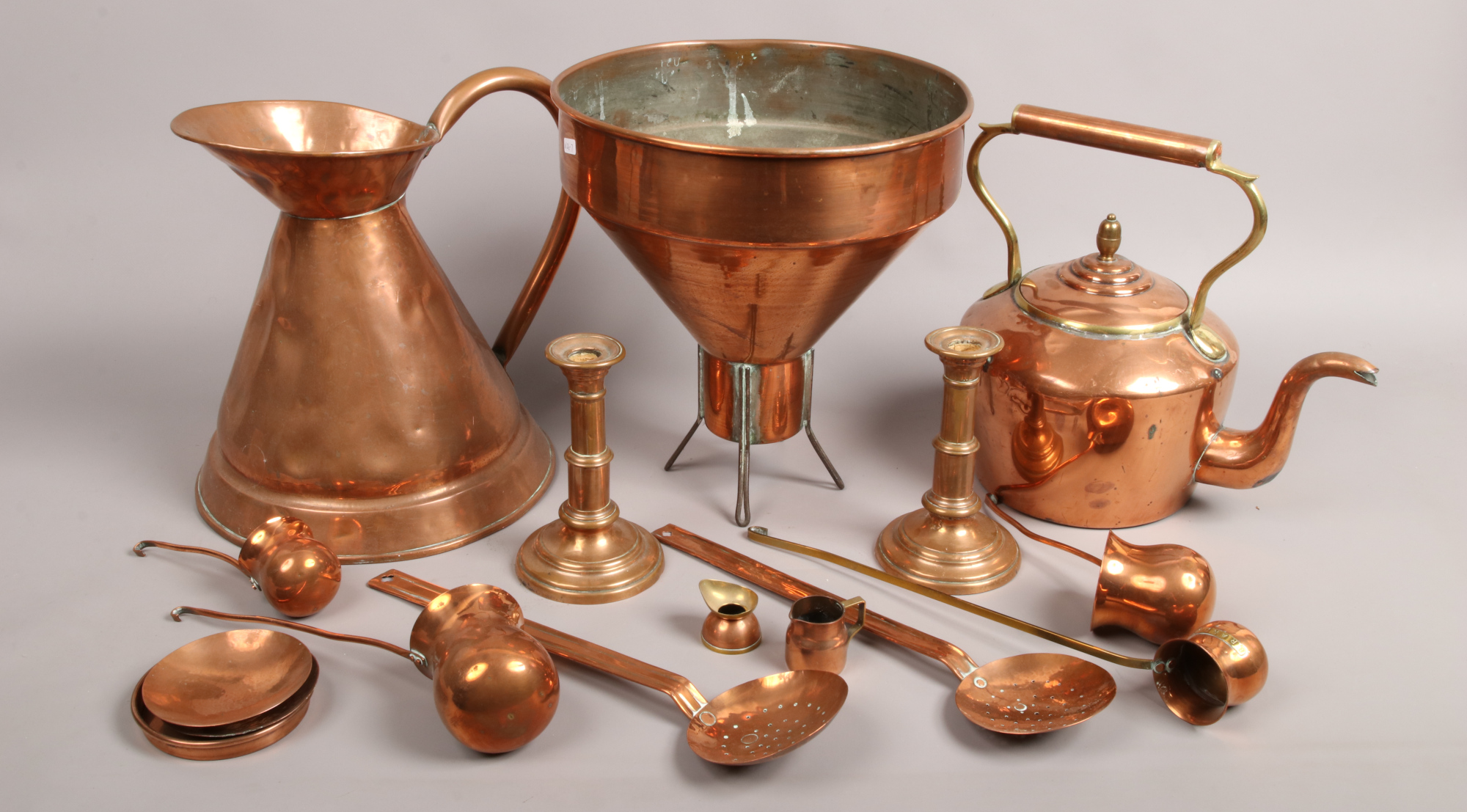 A collection of copperwares; large kettle jug and funnel, along with candlesticks, ladles etc.