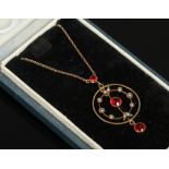 A cased Edwardian 9ct gold pendant on chain set with red paste stones and seed pearls.