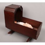 A vintage mahogany rocking dolls crib and antique fully jointed doll with moving eyes and sound.