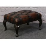 A deep buttoned leatherette footstool.