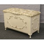 An upholstered painted blanket box raised on small cabriole legs.