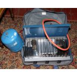 A camping stove in carry case and an empty gas bottle.