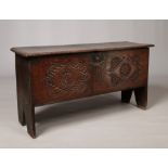 A 17th century boarded oak coffer. With exposed tenons to the side planks, carved medallions to