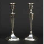 A pair of George V weighted silver table candlesticks. The reeded tapering columns are engraved with