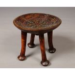 A West African tribal hardwood stool carved from one piece. With dished seat inlaid with multi