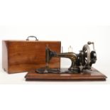 A vintage hand cranked Superba sewing machine in walnut and mahogany case. Ornamented with gilding