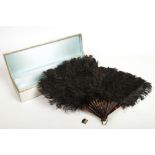 An early 20th century French black ostrich feather fan in silk mounted box. With faux