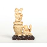 A Japanese Meiji period carved ivory vessel surmounted by two figures, one holding a fish and the