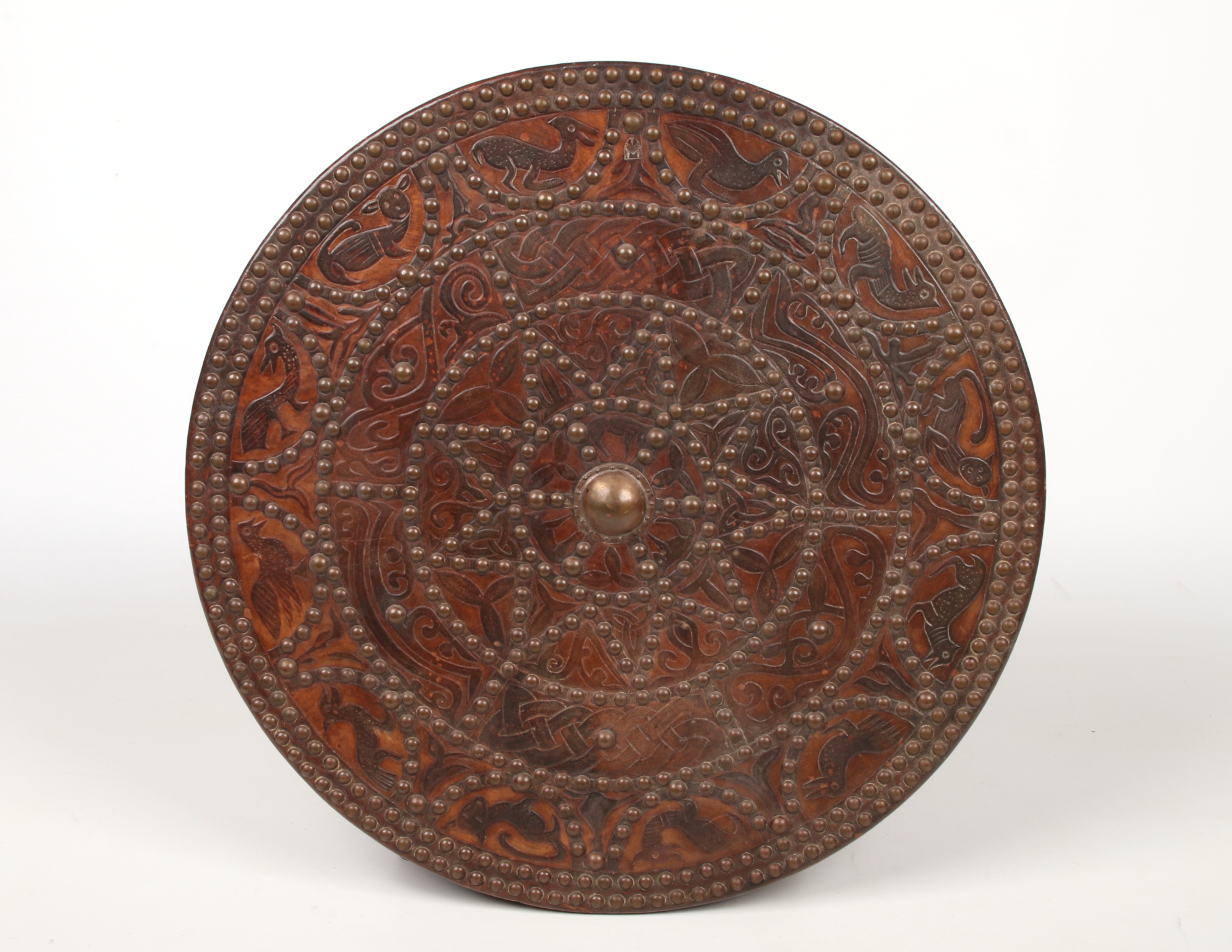 A decorative leather clad roundel shield adorned with brass studwork and tooled with animals and