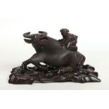 A Chinese early 20th century carved hardwood model of a recumbent water buffalo with a child