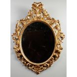 A 19th century Florentine carved giltwood oval hall mirror. Decorated with scrollwork and having