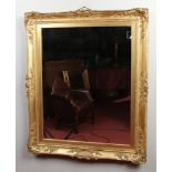 A wall mirror in ornate swept gilt frame, 118cm x 97cm.Condition report intended as a guide only.