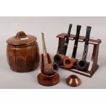 Four vintage pipes and two pipe racks, along with an oak tobacco jar.