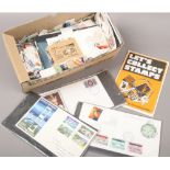 A box of mostly loose British stamps, postcards and first day covers.