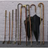 A collection of wooden shaft golf clubs, walking sticks and umbrellas.