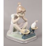 A Lladro figure of a young girl watching a cat on weighing scale.Condition report intended as a