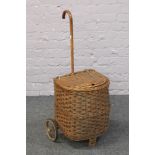 A wicker shopping trolley with curved handle.