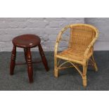 A child's rattan arm chair, along with a turned wooden stool.